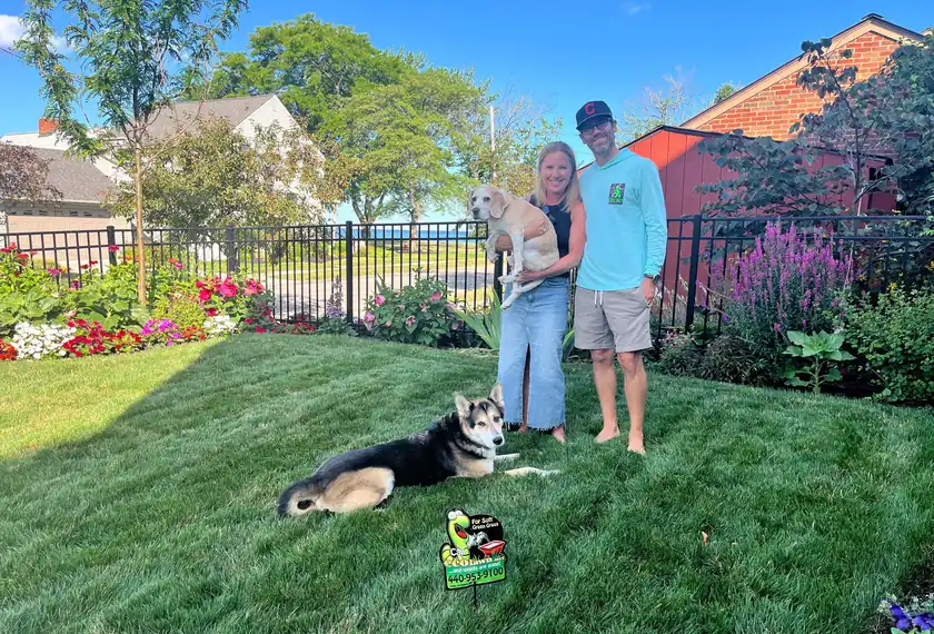 Ecolawn customers and their two dogs on a thick, green lawn beside their flower beds