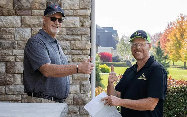 An Ecolawn team member handing over a written lawn plan at a front door